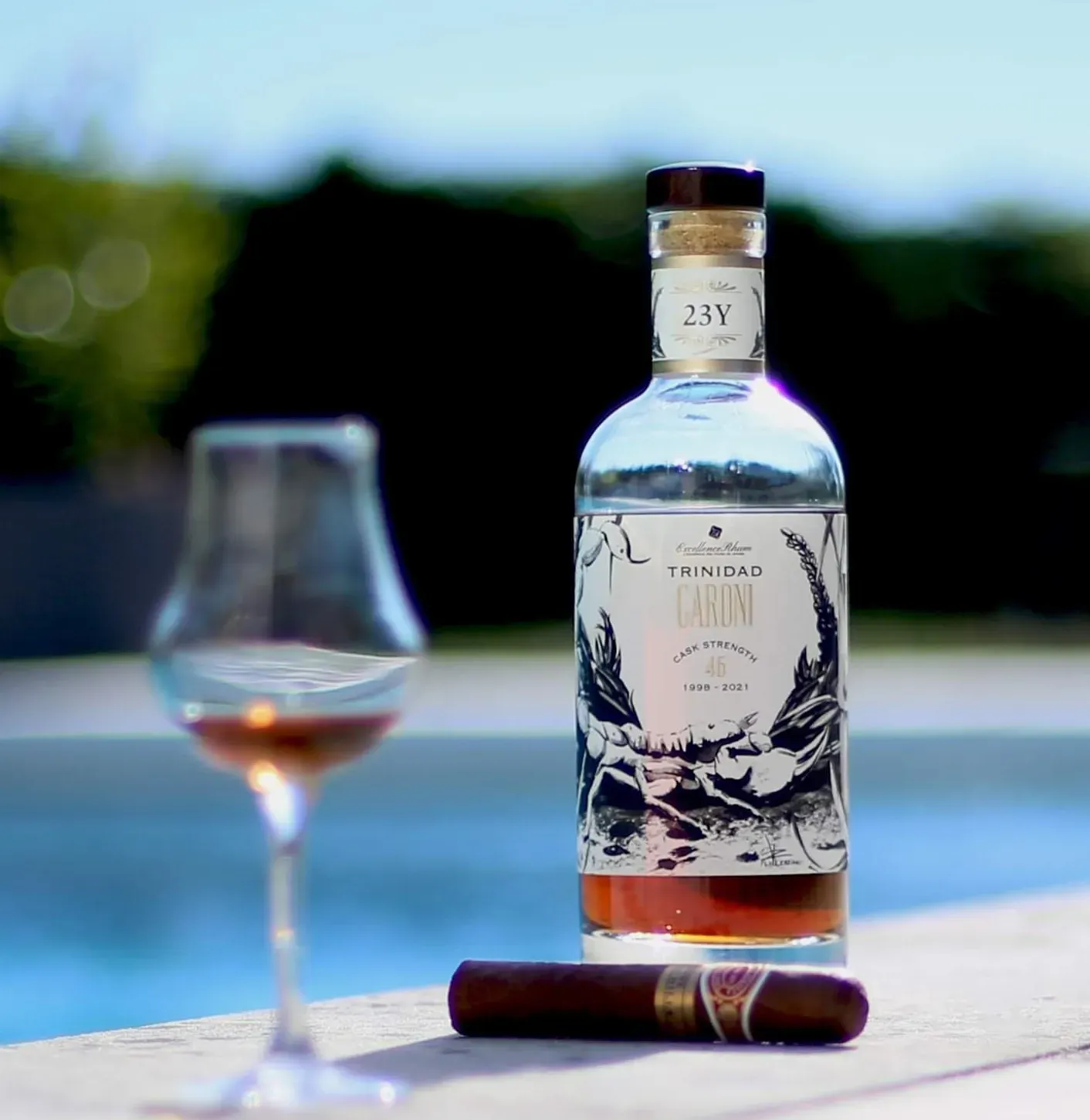 Verre de rhum Caroni accompagné d'un cigare, sur fond sombre