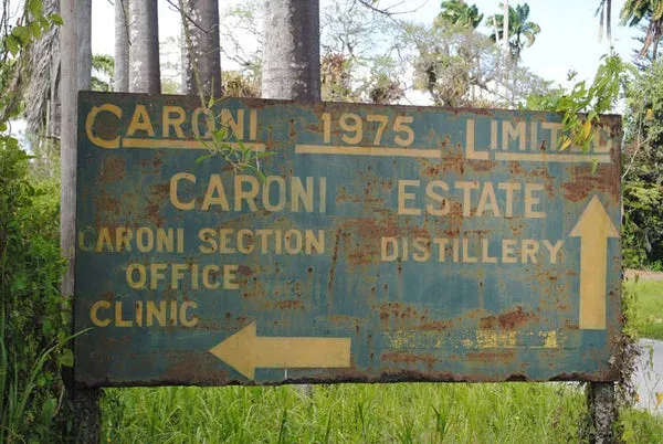 Panneau routier rouillé signalant la distillerie Caroni, à l'abandon