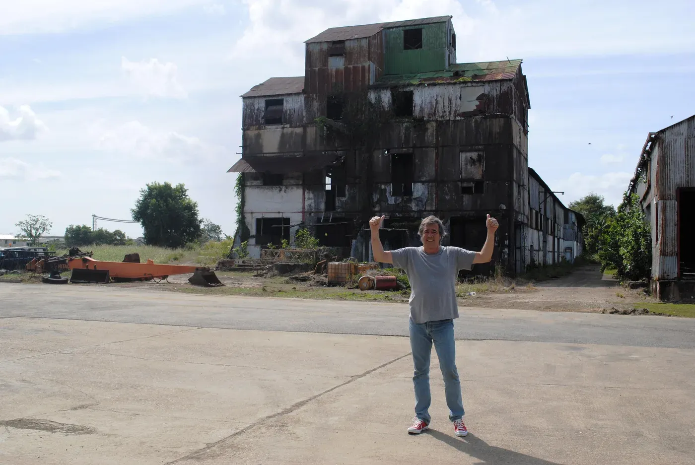 Luca Gargano, bras levés, devant le bâtiment en ruine de la distillerie Caroni